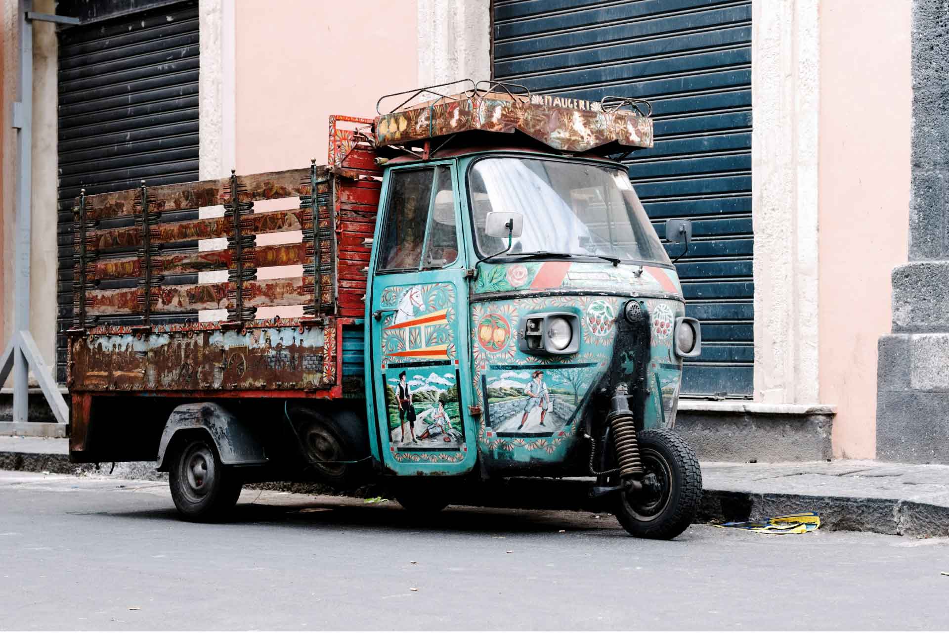 catania Un’ape-car in primo piano su una strada urbana della città, l'atmosfera autentica del quotidiano siciliano.
